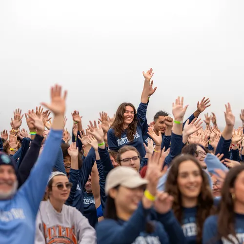 Group of students with hands raised before Annual Plunge
