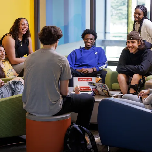 Eight students sitting in a study lounge, computers open, talking and laughing