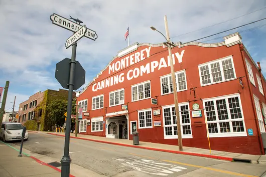 The historic Monterey Canning Company building stands along a coastal street, reflecting the region’s rich cultural and economic history.