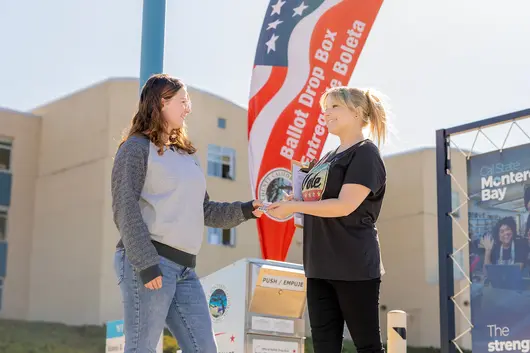People chatting beside a flag on campus