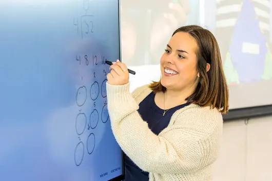A student writing on the digital board