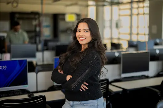 A student standing inside a computer lab in the business and information technology building