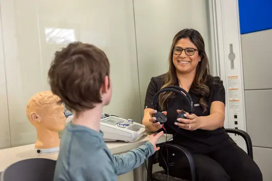 Professor conducting a listening test on a child.