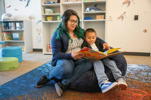 Bianca Estrada reading a book with a child in the library