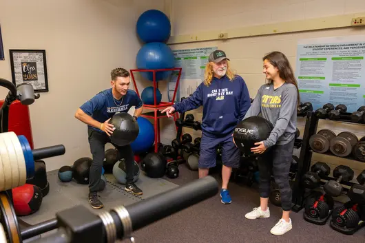 Students with teacher in gym lifting weights