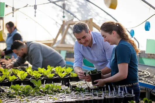 Professor and student in campus greenhouse planting during class