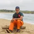 Person sitting on a beach wearing bright orange pants facing the camera