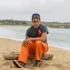 Person sitting on a beach wearing bright orange pants facing the camera
