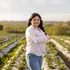 Portrait of an agricultural, plant and soil science student standing in a field smiling looking at the camera with her arms crossed.