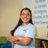 Student standing sideways with her arms crossed smiling for a portrait inside.