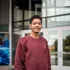 Student standing and smiling in front of a building for a portrait.