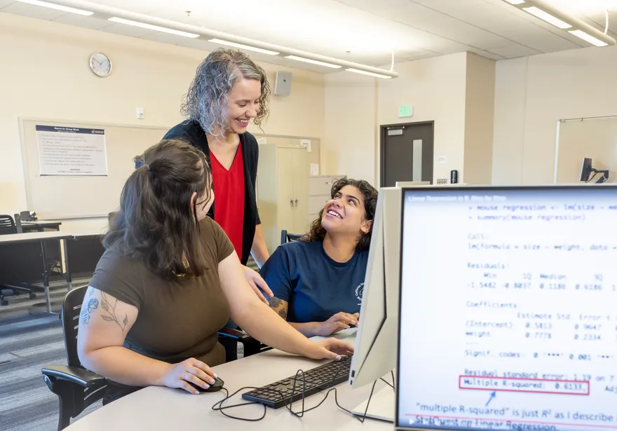 Two students looking up to a teacher at a desk