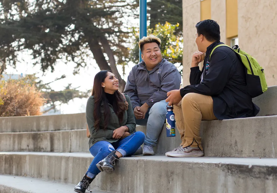 3 students sitting next to each other talking