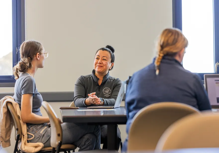 Three people sitting at tables with laptops