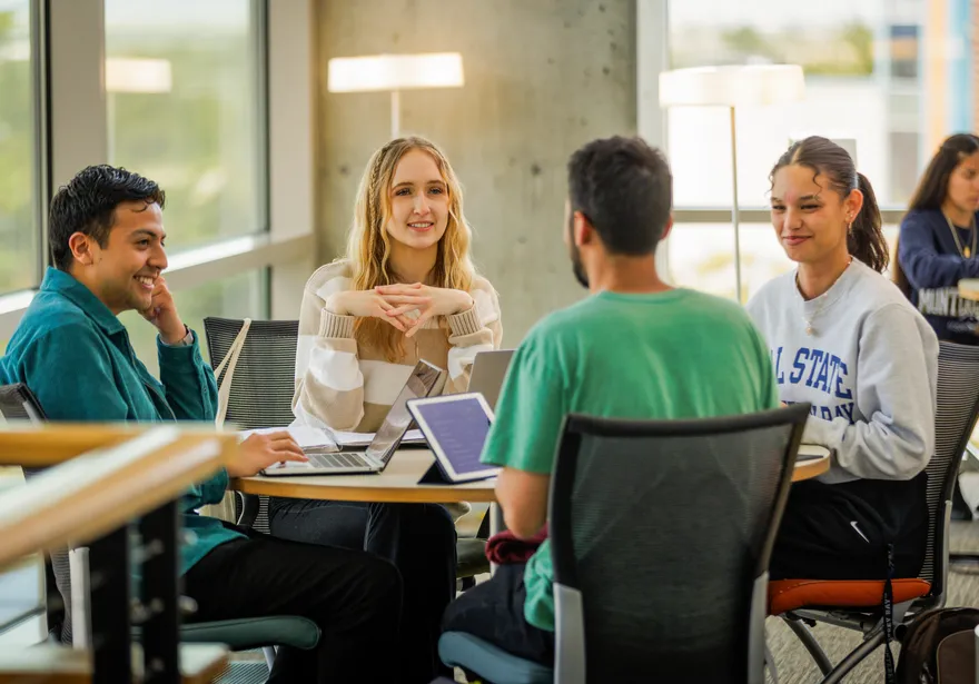 4 students studying at a library table
