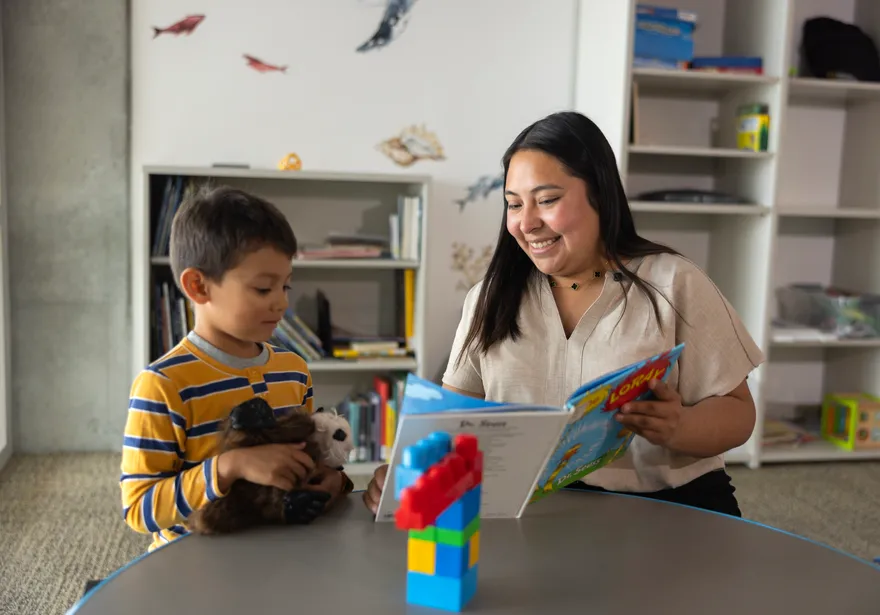 Student reading a story to a child in a classroom.