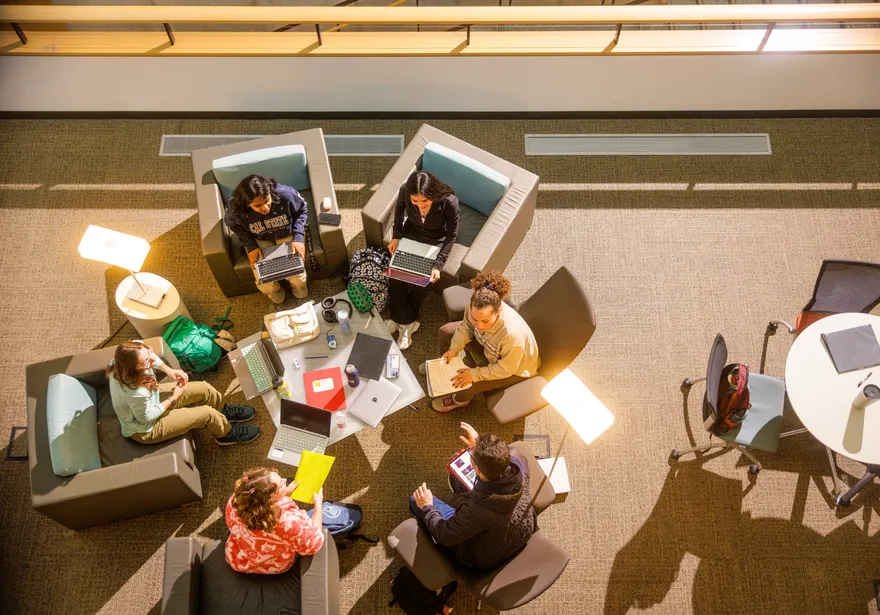 Students are sitting around the table in the library space