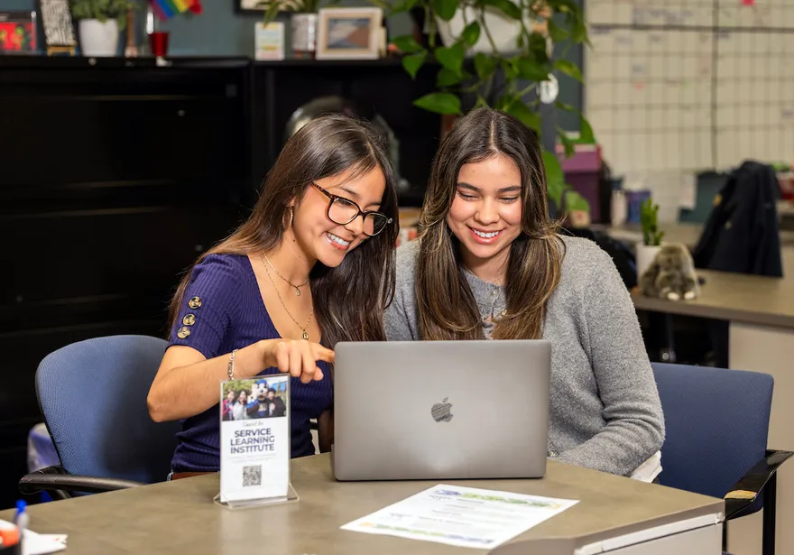 Two students reviewing content on a laptop while working together at a table.