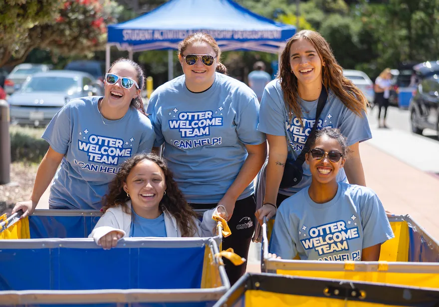 A group of student ambassadors smiles together while welcoming new students at a campus event.