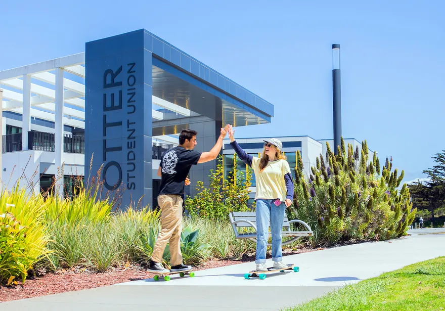 Two people hi fiving in front of the otter student union