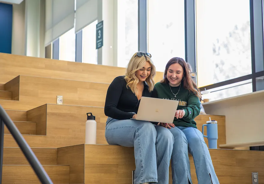 Two students sitting in the OSU looking at a laptop