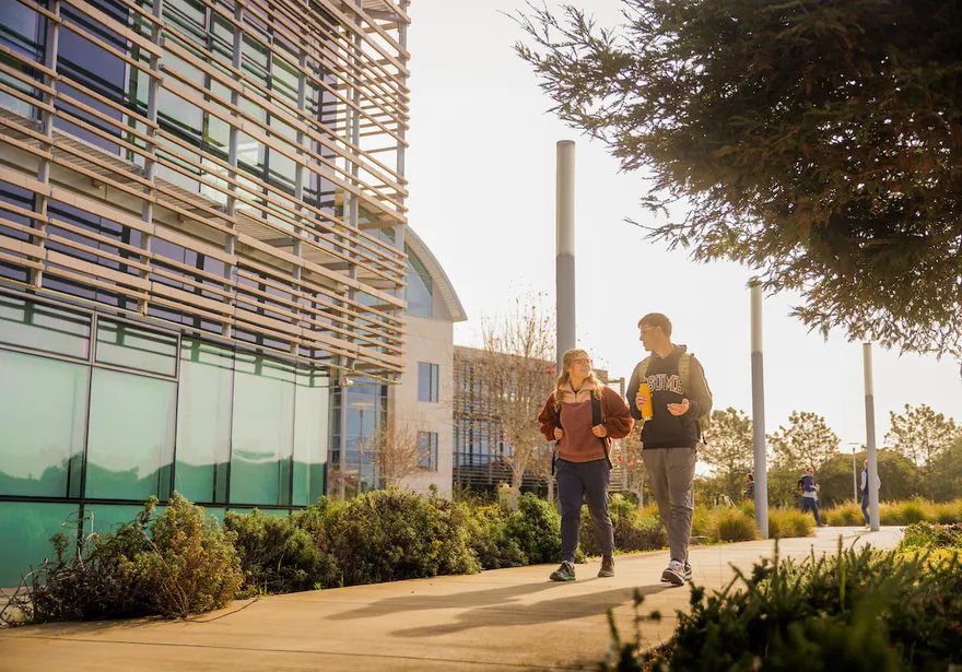 Two students walking along the BIT building and talking