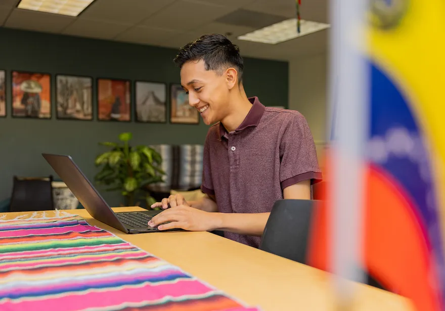 Student typing on a laptop inside El Centro.