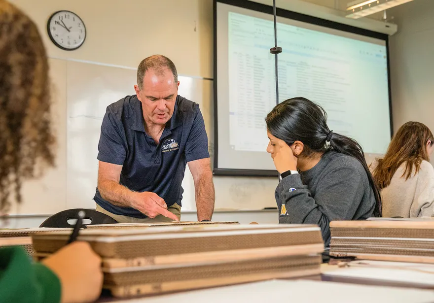 A professor speaking to a student in a classroom