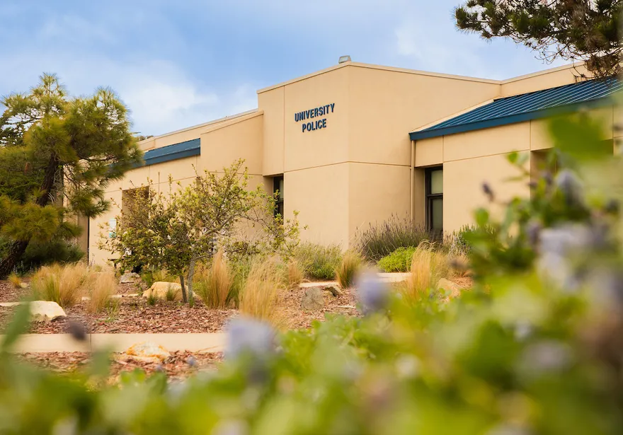 The university police building sits within a landscaped campus setting, reflecting safety and community presence.