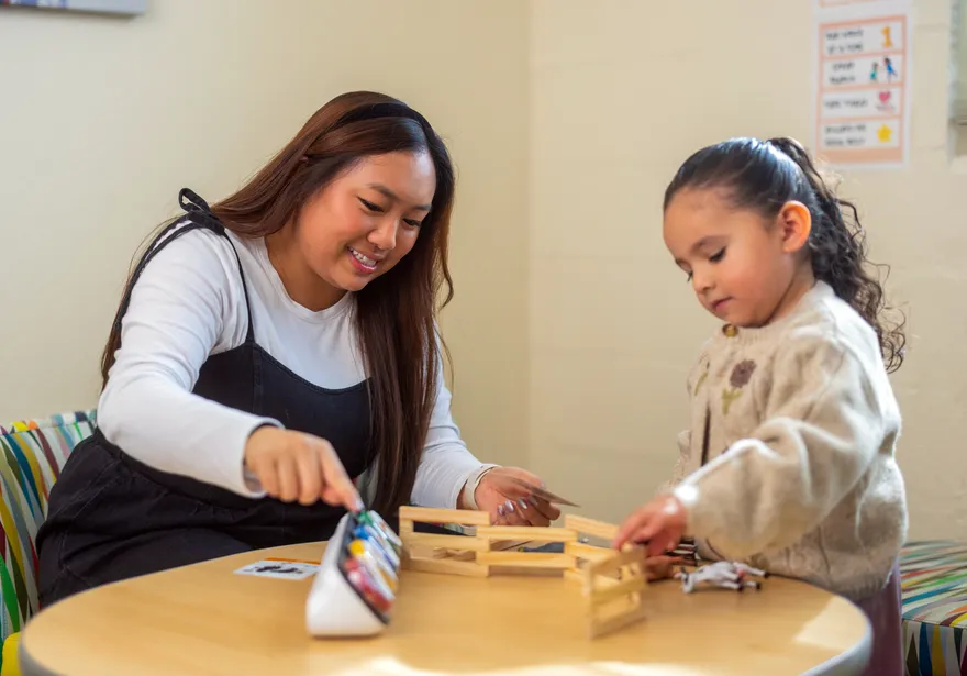 Student collaborating with a child and playing with some toys with her.