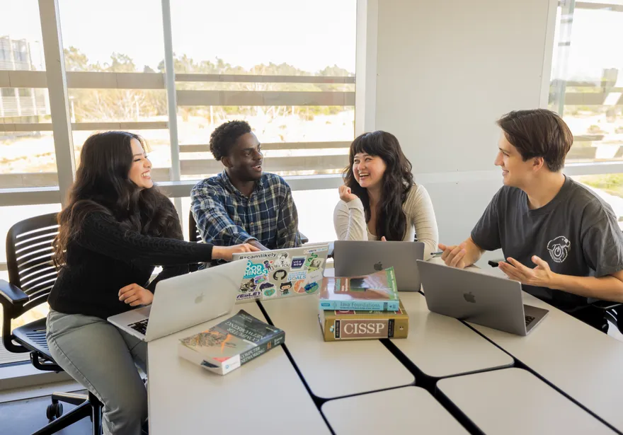 A group of students sitting down at a desk and collaborating