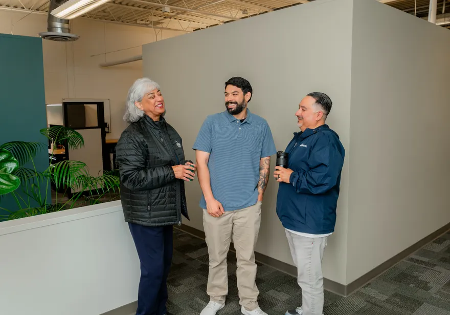 CSUMB staff enjoy a friendly hallway chat near their office space, smiling and sharing a light moment during the workday.