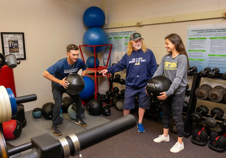 Students with teacher in gym lifting weights