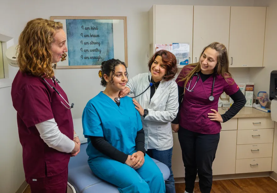 A professor giving a presentation to nursing students in scrubs about checking someones pulse