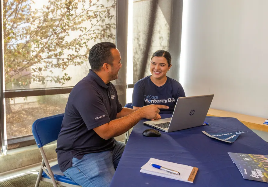 Two students sitting at a table with a laptop