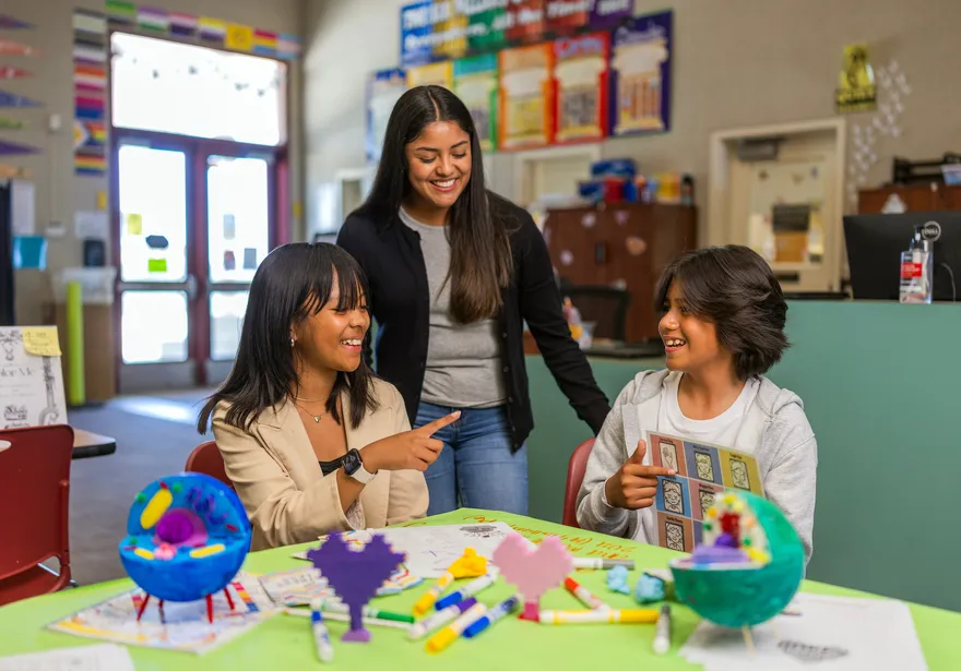 A social work credential student in a classroom teaching two kids