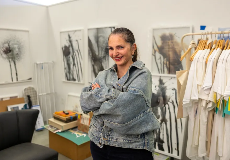 A woman standing and smiling with her arms crossed for a portrait in an art gallery.