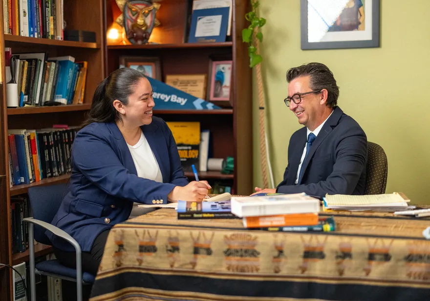 Two people having a discussion at a table and smiling at each other