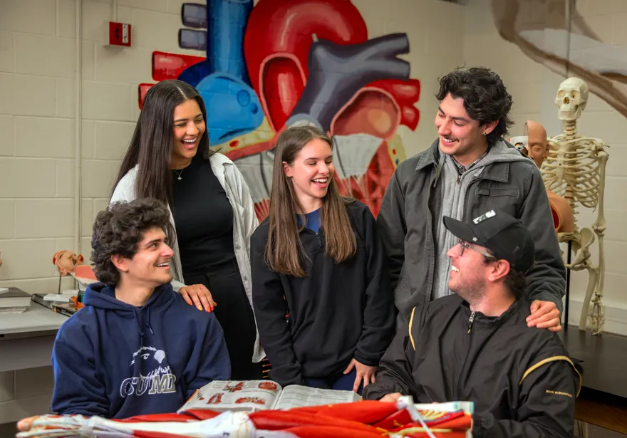 A group of kinesiology students grouped together laughing and smiling