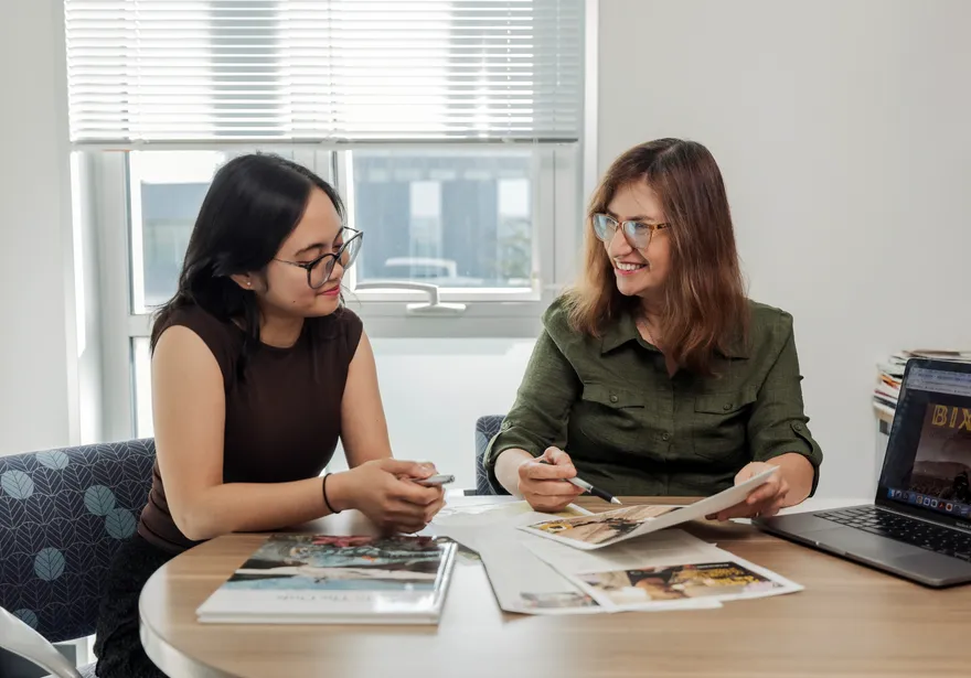 Student and Professor sitting at a table looking at a paper together