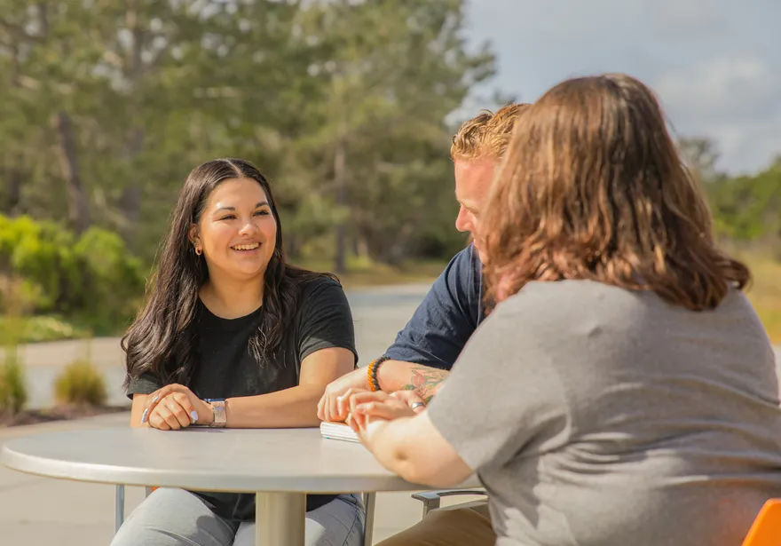 Three people seated at a table outdoors