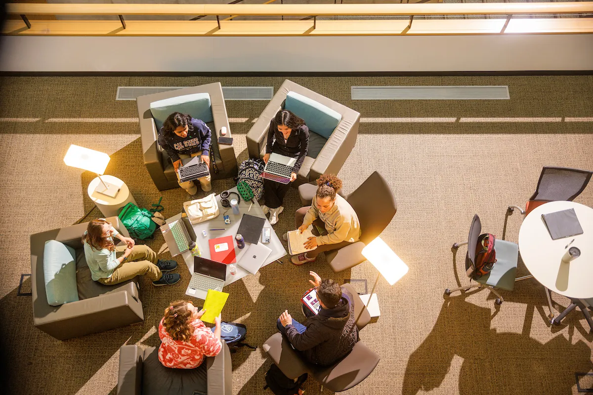 Students are sitting around the table in the library space